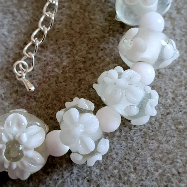 Bracelet réalisé en perles de verre fleurs blanches monté sur des éléments en argent.