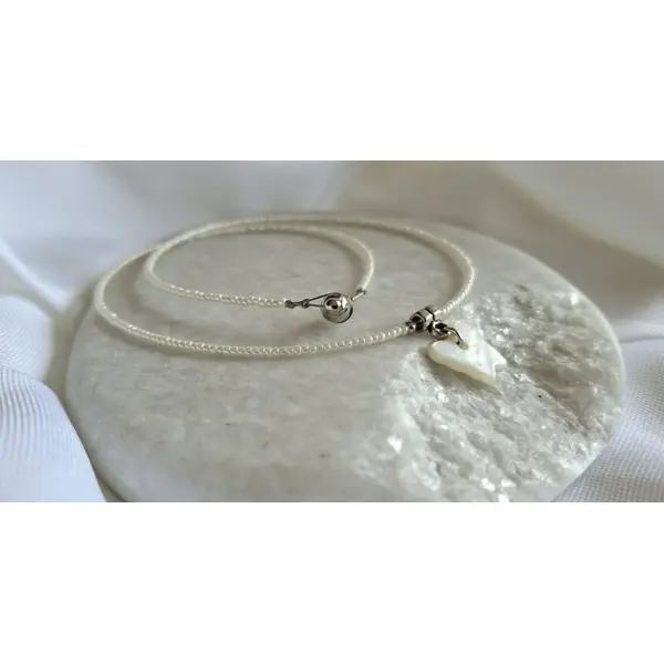 Collier ras de cou 39 cm en perles de rocaille blanches, pendentif papillon en nacre blanche, fermoir aimanté