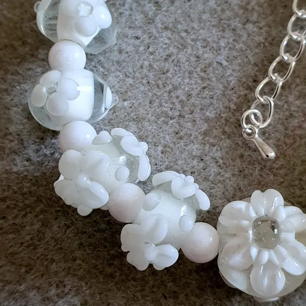 Bracelet réalisé en perles de verre fleurs blanches monté sur des éléments en argent.